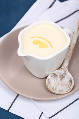 Delicate sauce in pitcher on wooden table close-up