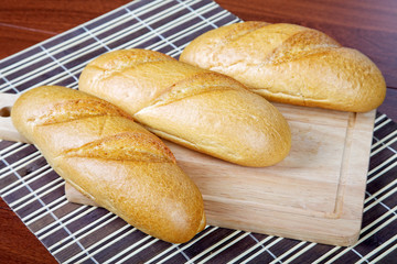 Three long loafs  on a chopping board