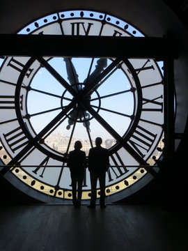 Two people silhouetted by huge clock