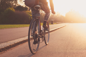 Young woman cycling in the park at sunset - obrazy, fototapety, plakaty