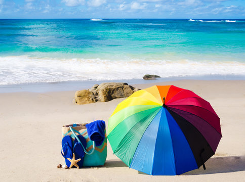 Summer background with rainbow umbrella and beach bag