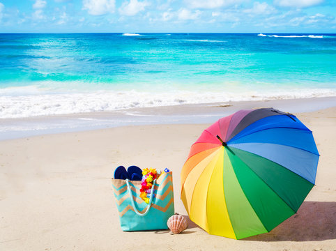 Fototapeta Summer background with rainbow umbrella and beach bag