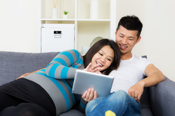 Asia pregnant woman with her husband using tablet at home