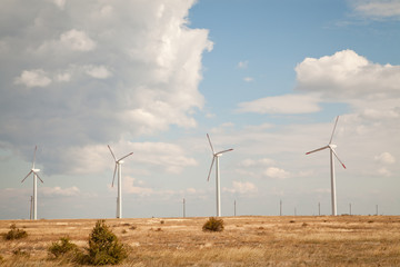 Wind turbine farm over the blue clouded sky