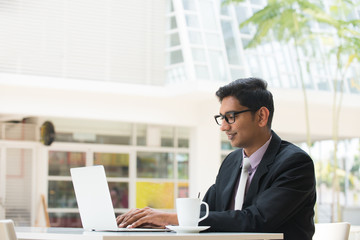 young indian business man on laptop and coffee