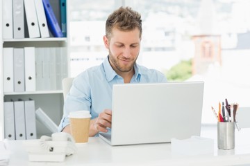 Smiling man working at his desk on laptop