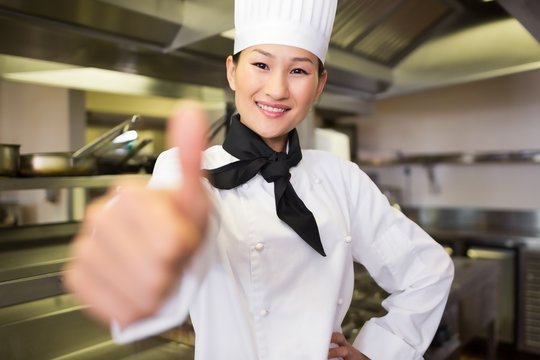 Smiling female cook gesturing thumbs up in kitchen