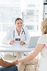 Confident female doctor with expectant couple