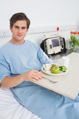 Man in gown having mean in hospital