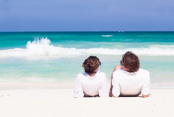 back view of young couple lying on beach