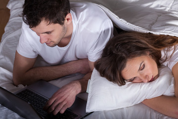 Sleeping wife and husband using computer