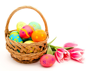 Colorful easter eggs in basket and flowers isolated