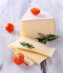 Tasty Camembert cheese with tomato and rosemary, on wooden