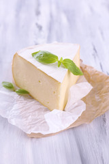 Tasty Camembert cheese with basil, on wooden table