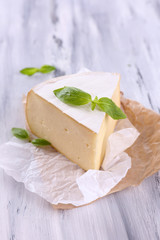 Tasty Camembert cheese with basil, on wooden table