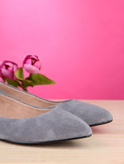 Fototapeta na wymiar Beautiful grey female shoes and flowers on pink background