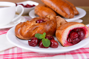 Fresh baked pasties with cherry on plate on table close-up