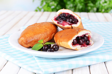Fresh baked pasties with currant on plate on table close-up