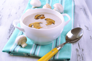 Mushroom soup in white pot, on napkin,  on wooden background