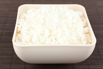 Cooked rice in bowl on bamboo background