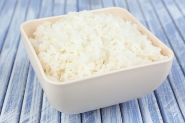 Cooked rice in bowl on wooden background