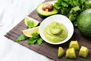 Fresh guacamole in bowl on wooden table