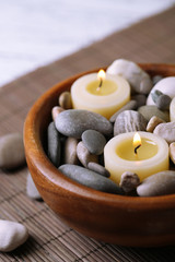 Composition with spa stones, candles on bamboo mat background