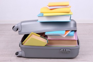 Books in suitcase on wall background