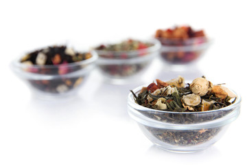 Different kinds of dry tea in bowls isolated on white