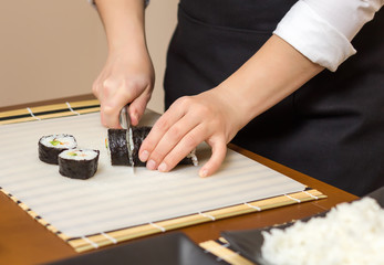 Closeup of woman chef cutting japanese sushi roll