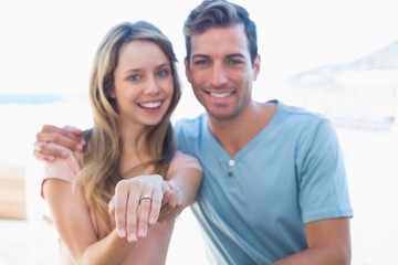 Fototapeta na wymiar Happy woman showing engagement ring besides man