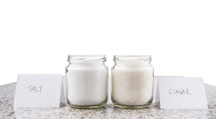 Salt and sugar in a glass bottle on granite surface