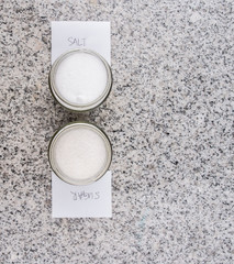 Salt and sugar in a glass bottle on granite surface