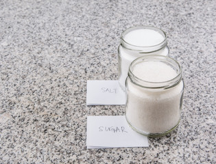 Salt and sugar in a glass bottle on granite surface