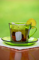 Tea cup with fresh lemons, closeup photo