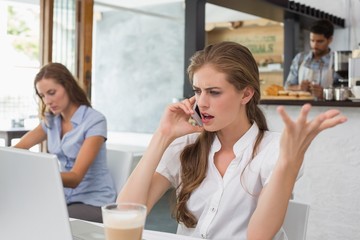 Fototapeta premium Annoyed woman using mobile phone in coffee shop