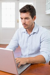 Concentrated man using laptop at table