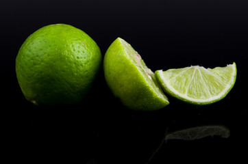 Citrus lime fruit half on black background, small green lemons