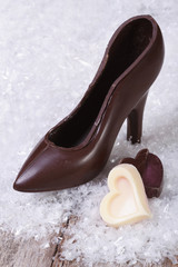 black chocolate shoe with candy hearts on the table. vertical