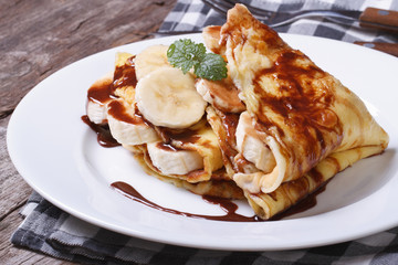 banana crepes with chocolate on a white plate