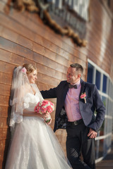 Fototapeta premium Bride and groom at wedding day kissing at park