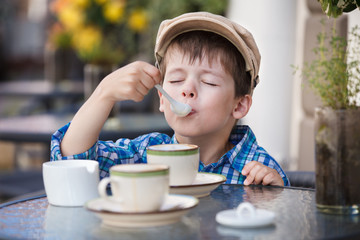 Little boy drinking milkshake in cafe