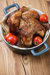 Bowl with baked spicy chicken and mini tomatoes, high angle view