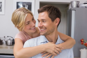Woman embracing man from behind in kitchen
