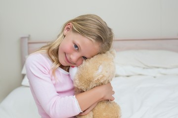 Young girl embracing stuffed toy in bed