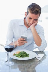 Young man text messaging at food table
