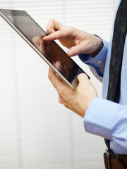 businessman standing and working on digital tablet, closeup