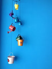 Foto op Plexiglas hanging small bucket on blue wall © happysunstock