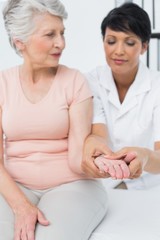 Obraz na płótnie Canvas Female physiotherapist examining a senior patients hand
