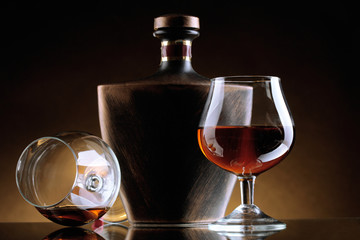 Glasses of brandy and bottle on brown background